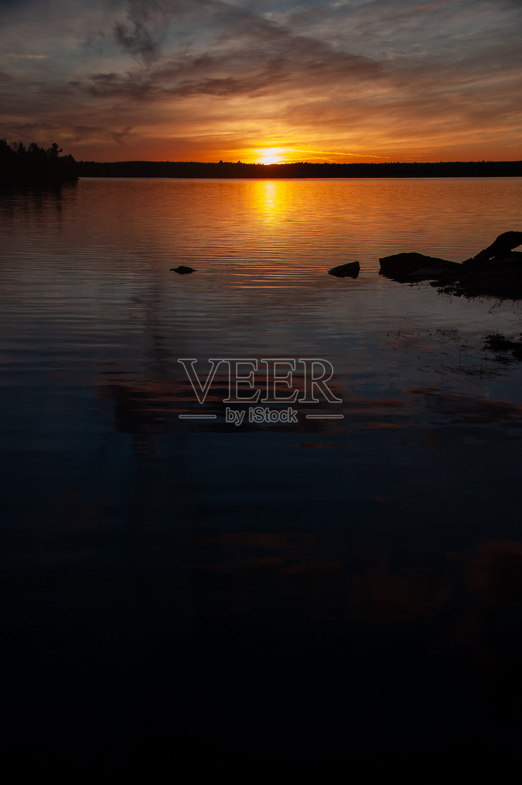 阴郁的日落映照在平静的湖面上，水中倒映着黑暗的影子照片摄影图片