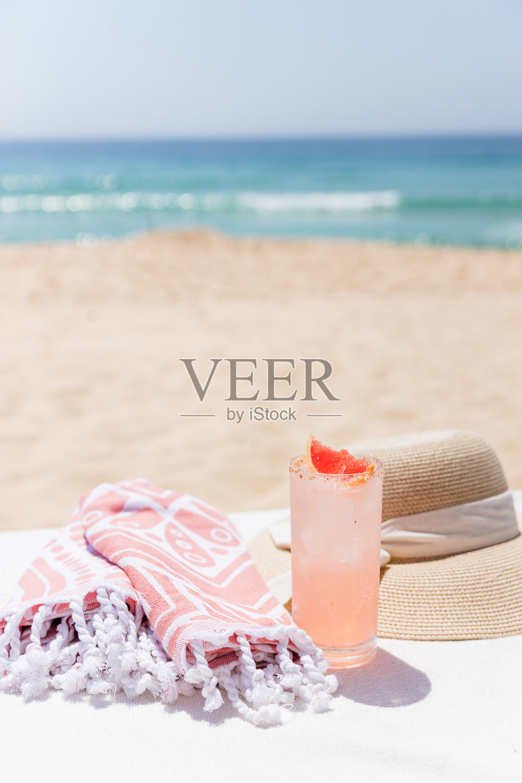 阳光明媚的海滩上有草帽、毛巾、太阳镜和平板电脑照片摄影图片