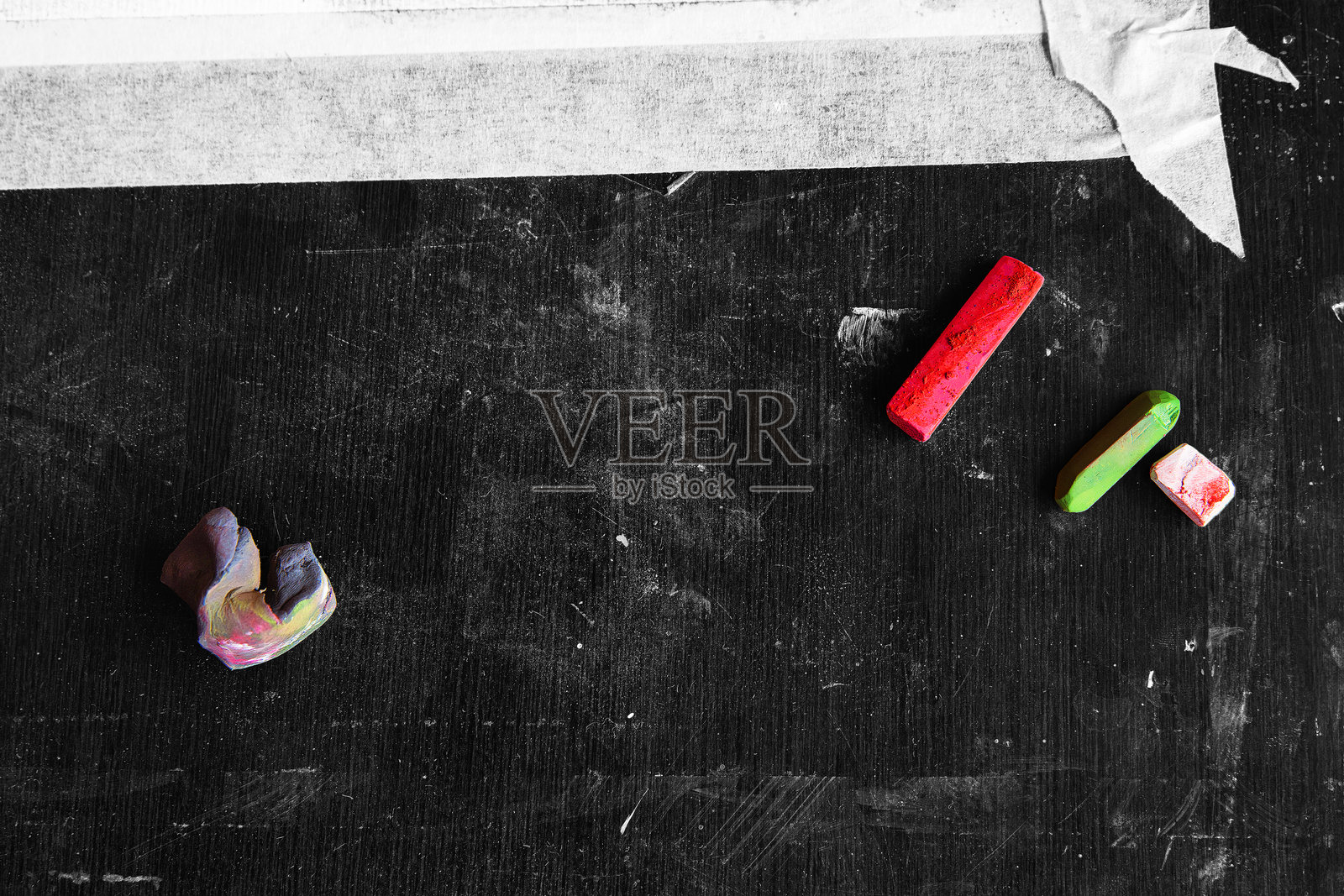 艺术工作空间，红色和绿色的粉彩棒以及一个橡皮擦放在深色单色纹理表面上照片摄影图片