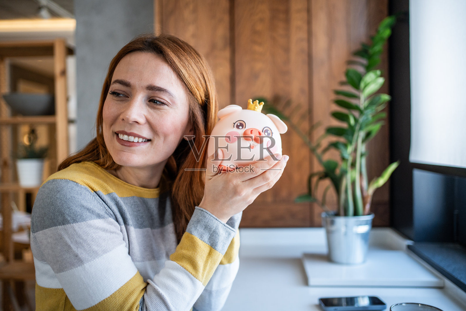 快乐的女人在家里微笑着拿着储蓄罐照片摄影图片