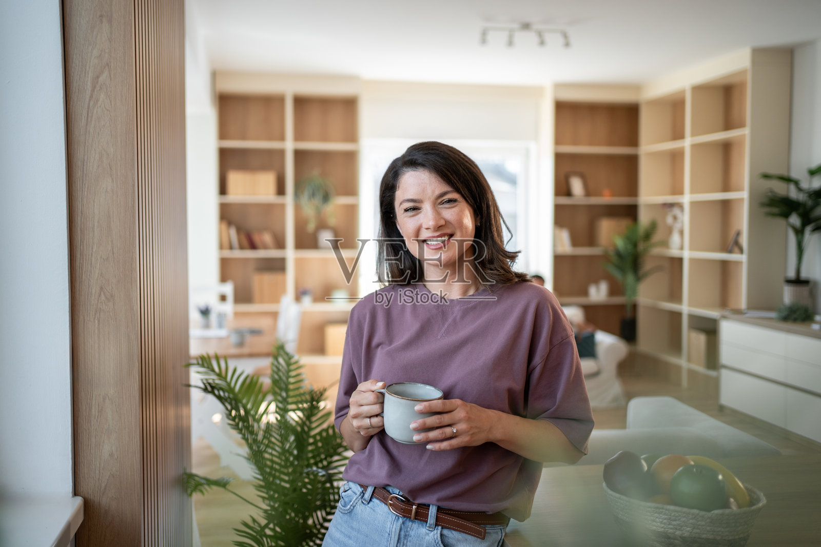 女人在现代公寓里微笑着拿着一个杯子照片摄影图片