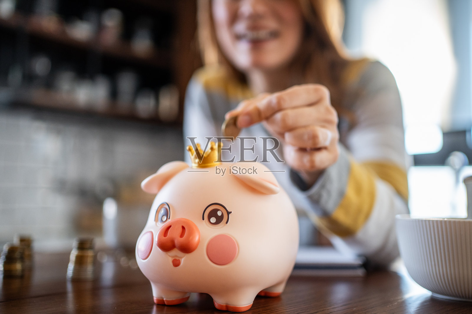 年轻女性在带皇冠的储蓄罐里存钱照片摄影图片