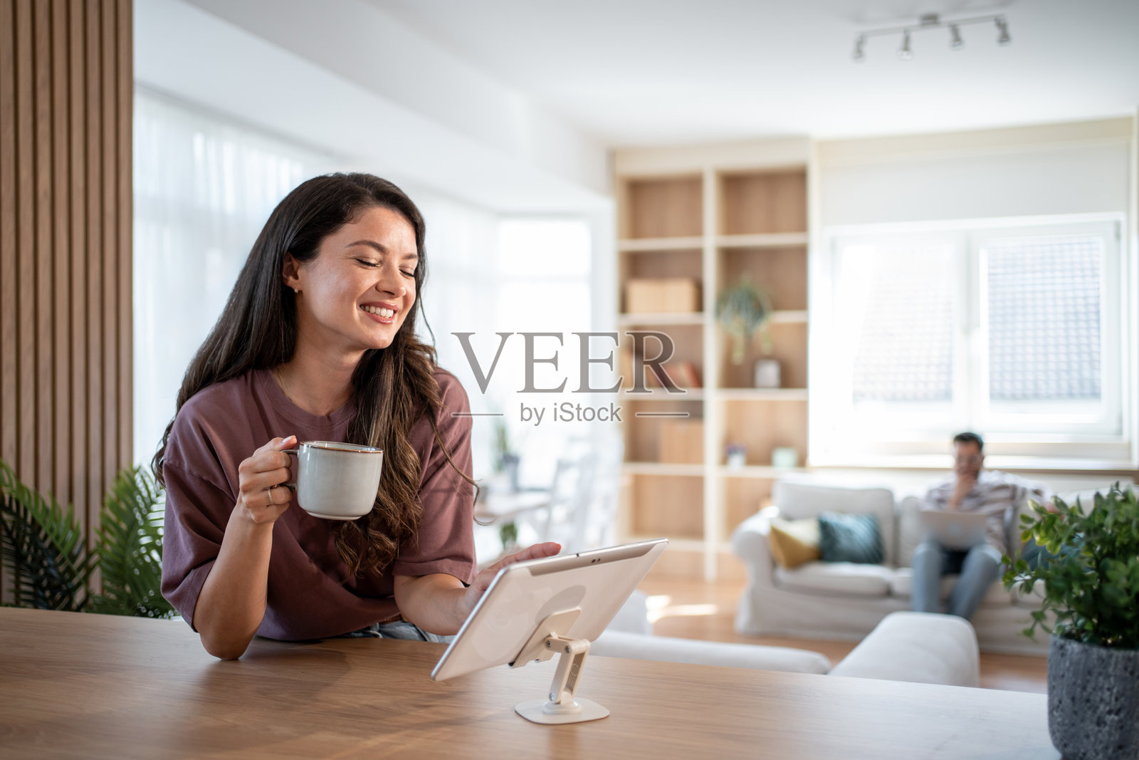 年轻女性在家中享受早晨咖啡并使用平板电脑照片摄影图片