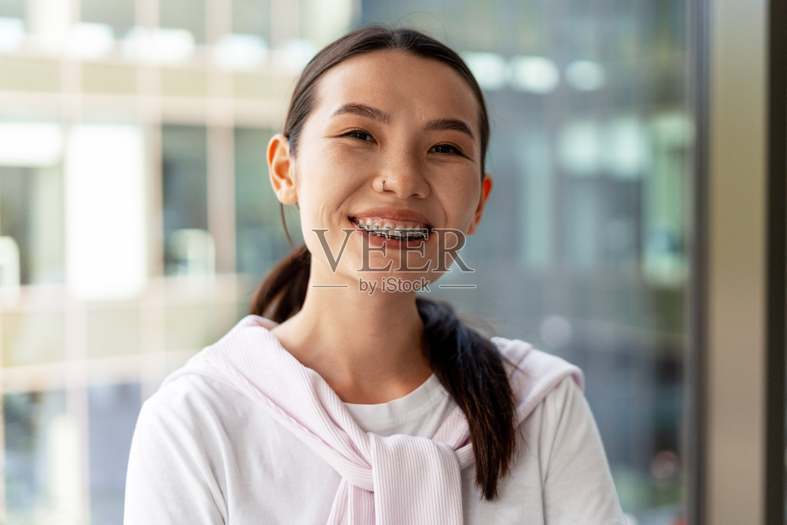 年轻的亚洲女性微笑，戴着牙套和鼻环照片摄影图片