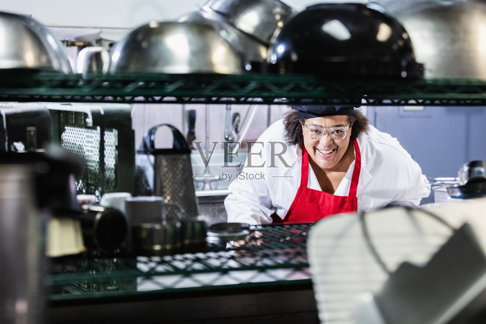 微笑着面对镜头的黑人女性厨师在餐厅厨房里照片摄影图片