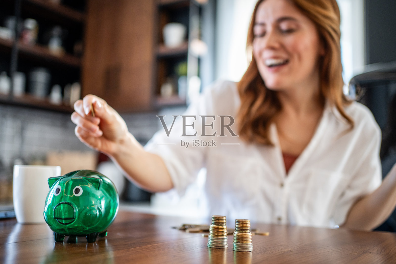 女人在家里把钱存进储蓄罐照片摄影图片