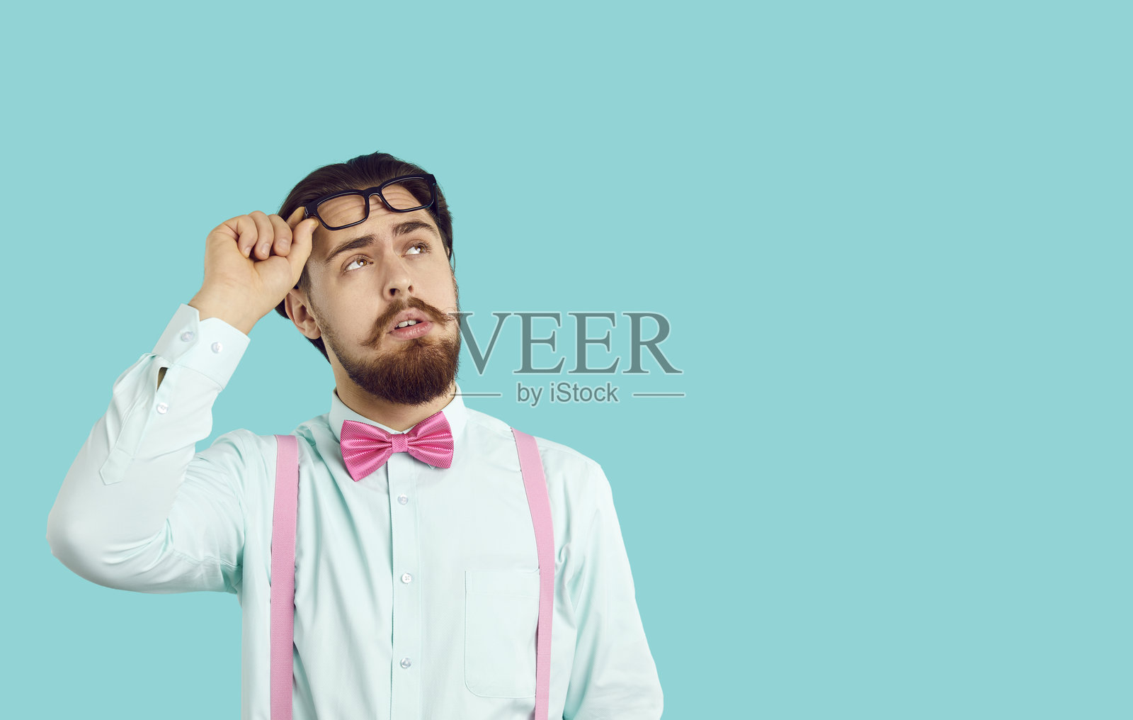 留着胡子的白人男子抬头，举起眼镜，穿着白衬衫。照片摄影图片