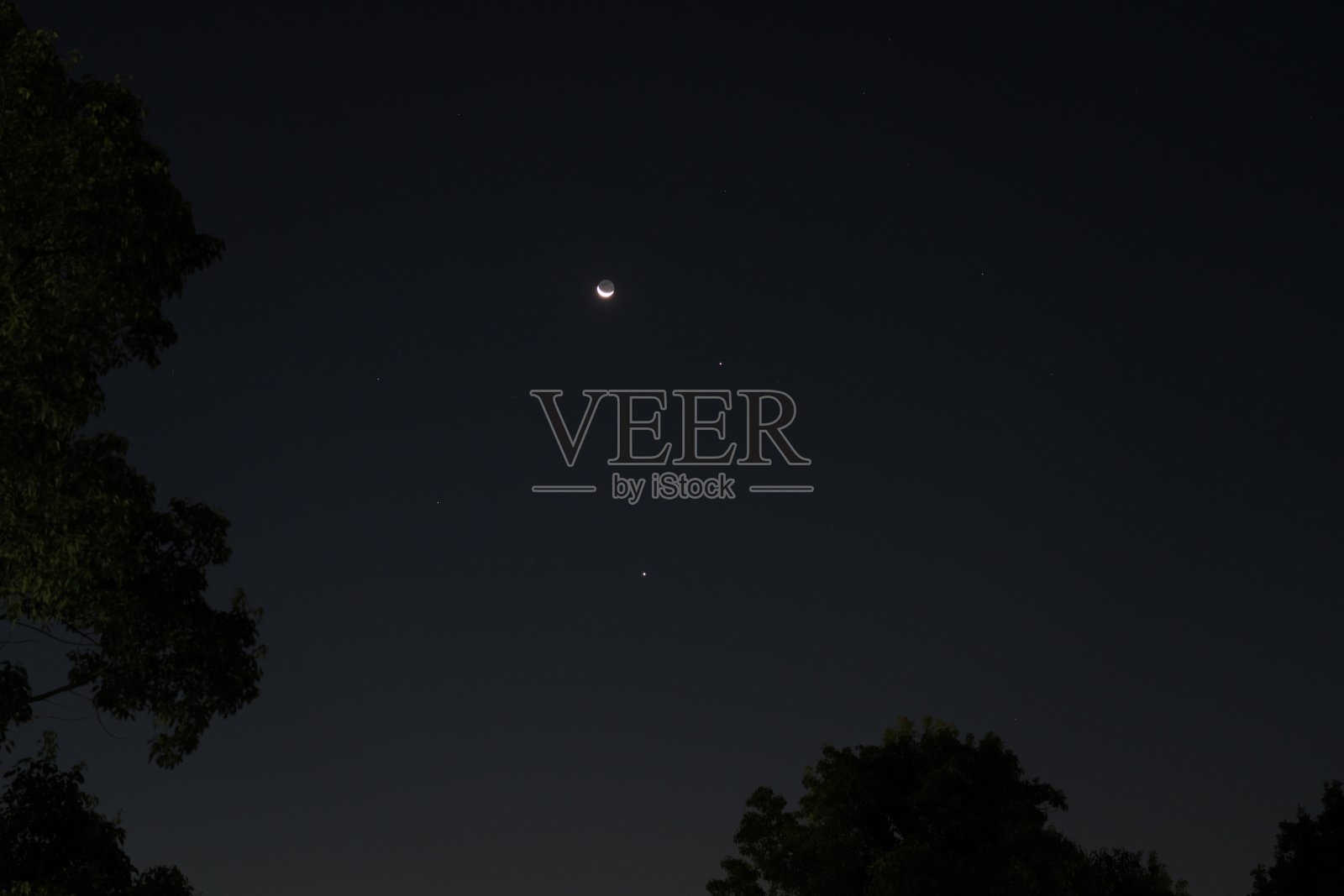 薄薄的月亮伴随着地球反射光，东边的天空中有木星和金星，清晨时分。照片摄影图片