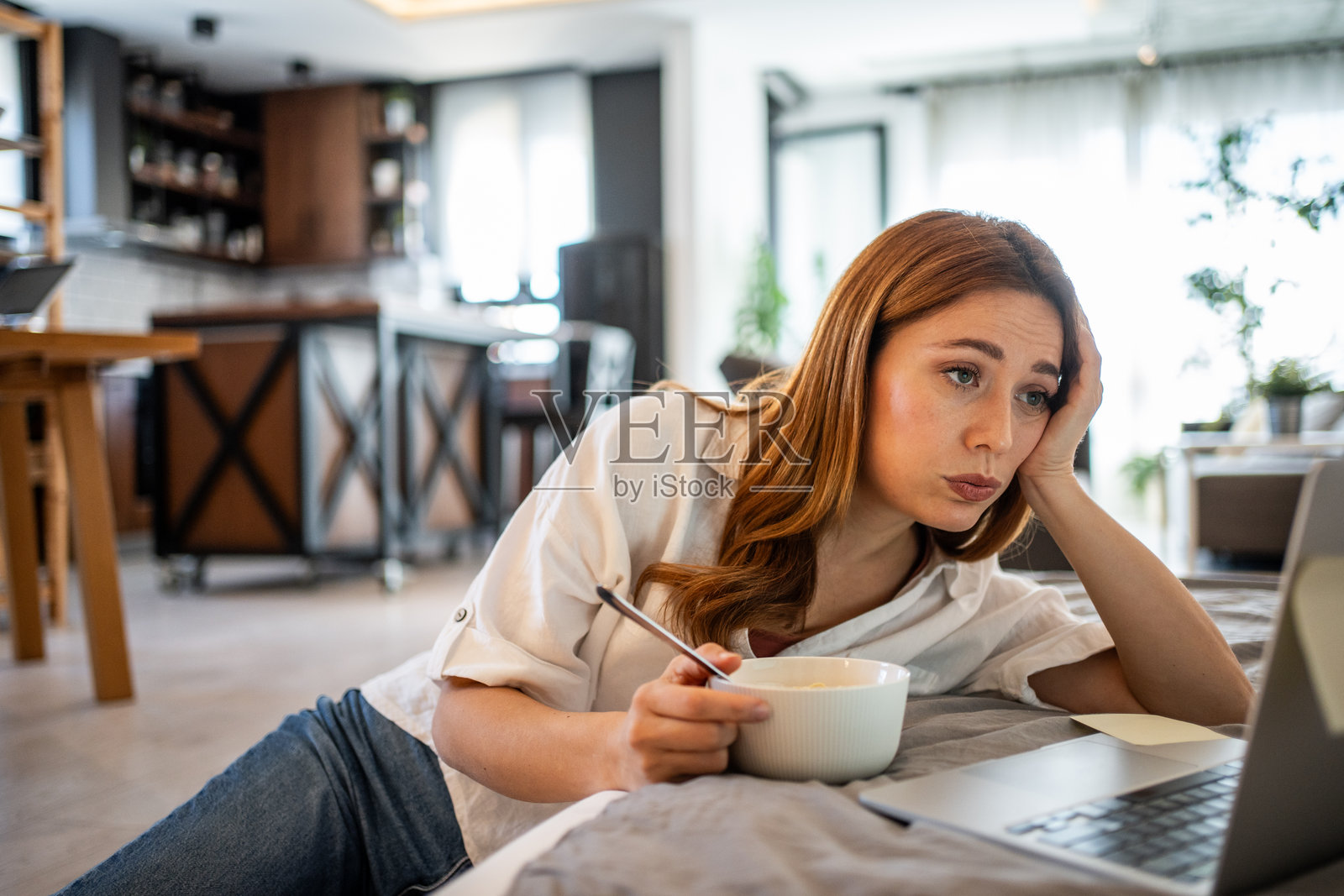 无聊的年轻女性在家吃早餐并工作照片摄影图片