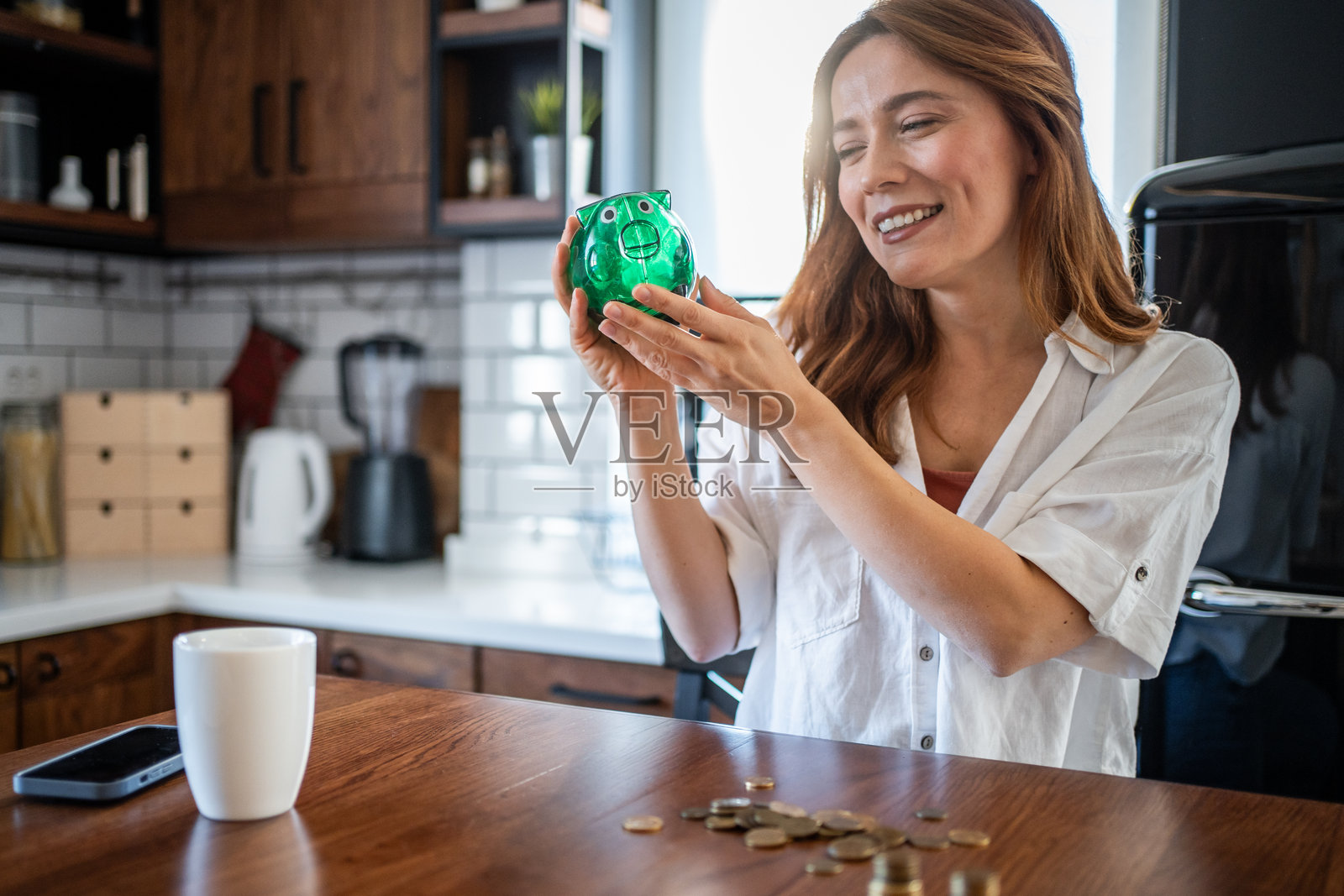 女人在家里用储蓄罐存钱照片摄影图片