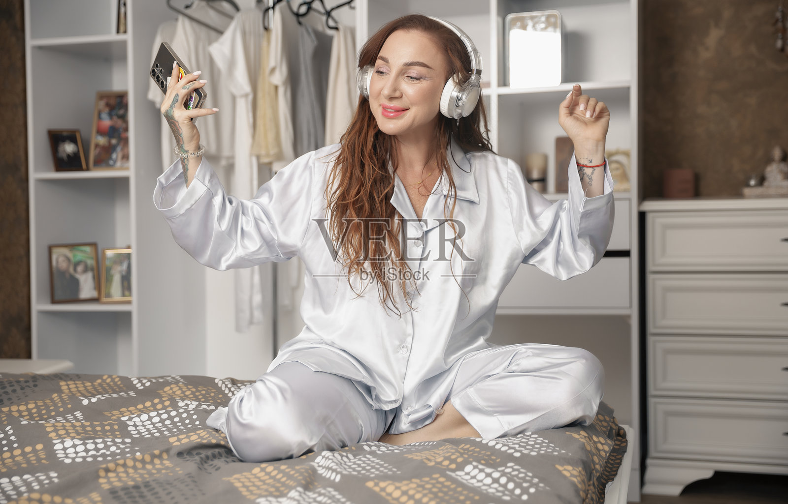 快乐的女人穿着睡衣在床上听音乐跳舞照片摄影图片