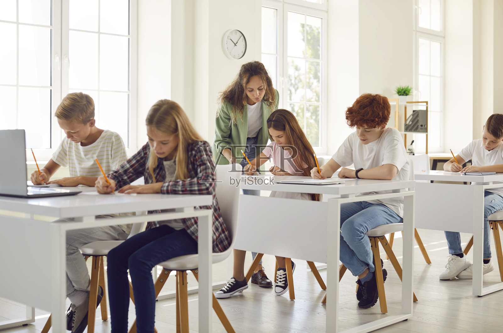 女教师在教室里俯身靠近一个女孩，特写镜头照片摄影图片