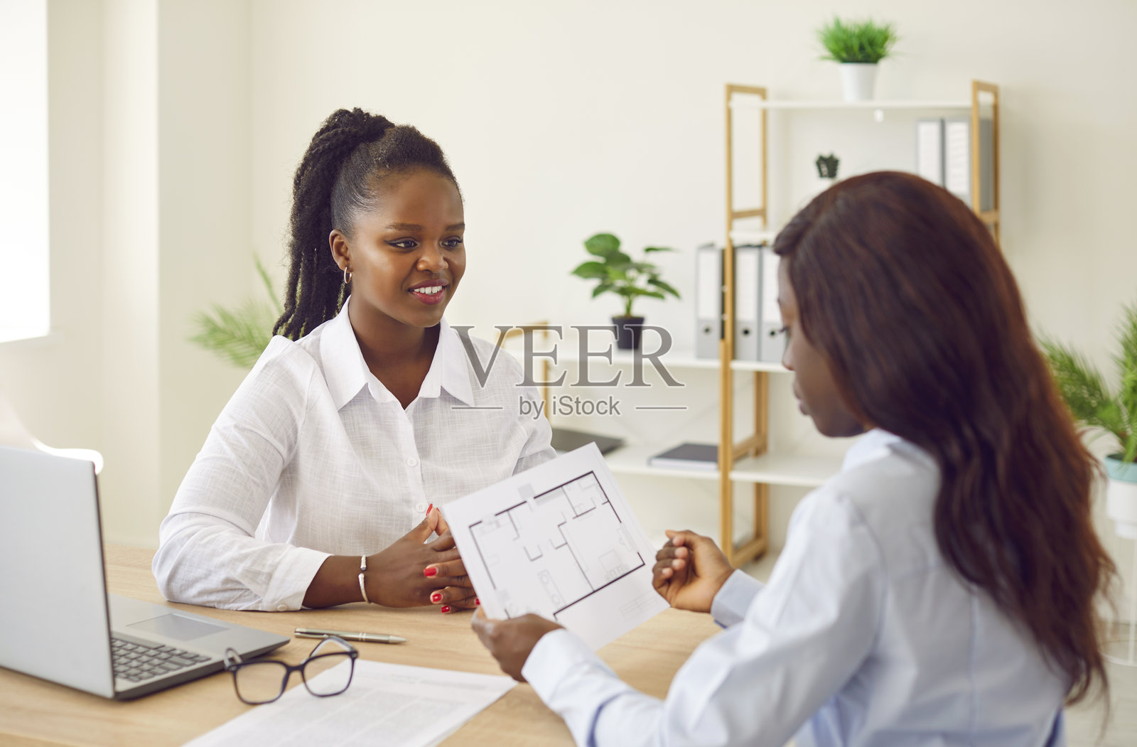 年轻的非裔美国女性在桌子前使用笔记本电脑，设计师，建筑师办公室咨询照片摄影图片