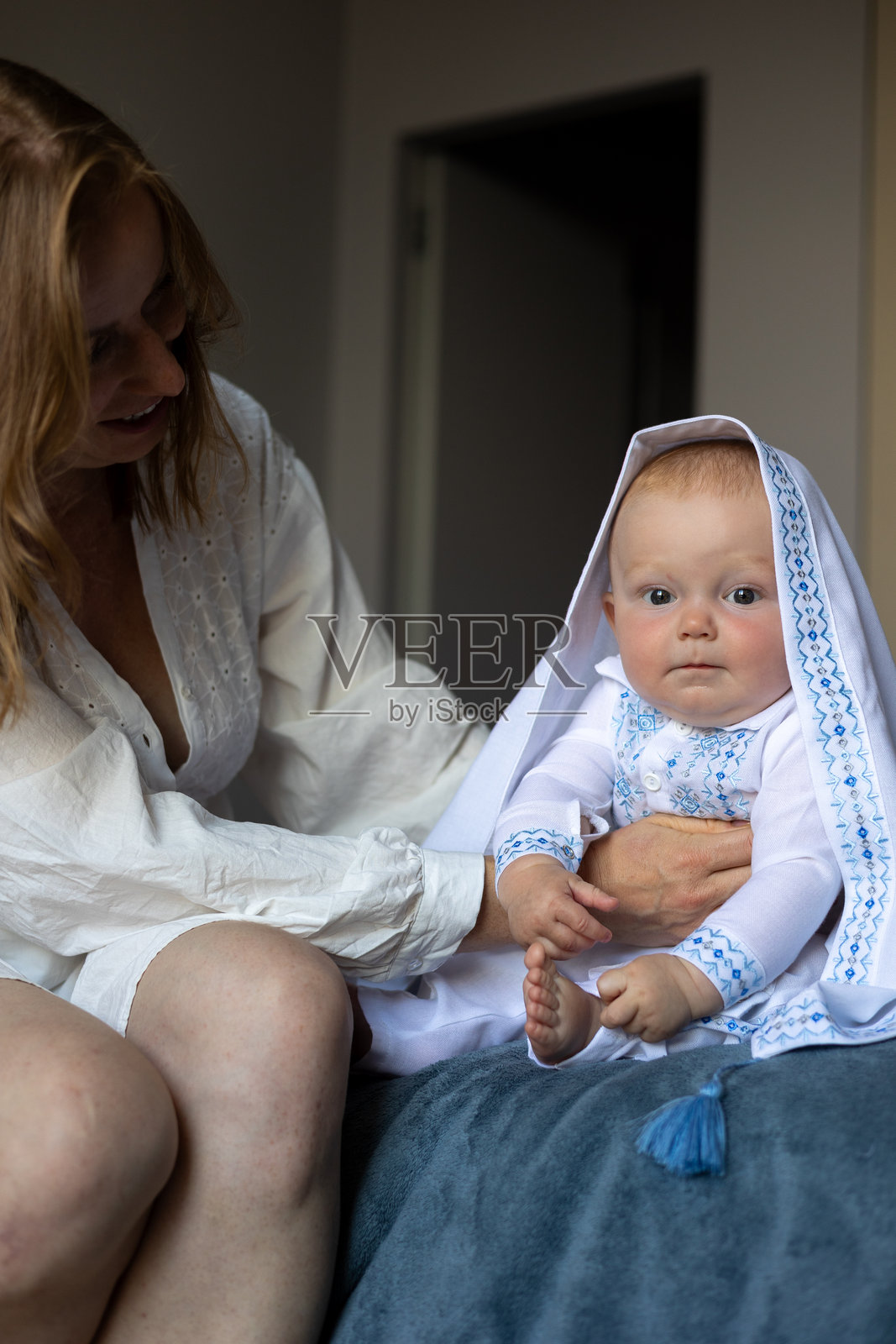 穿着刺绣白色服装的婴儿与母亲在家中照片摄影图片