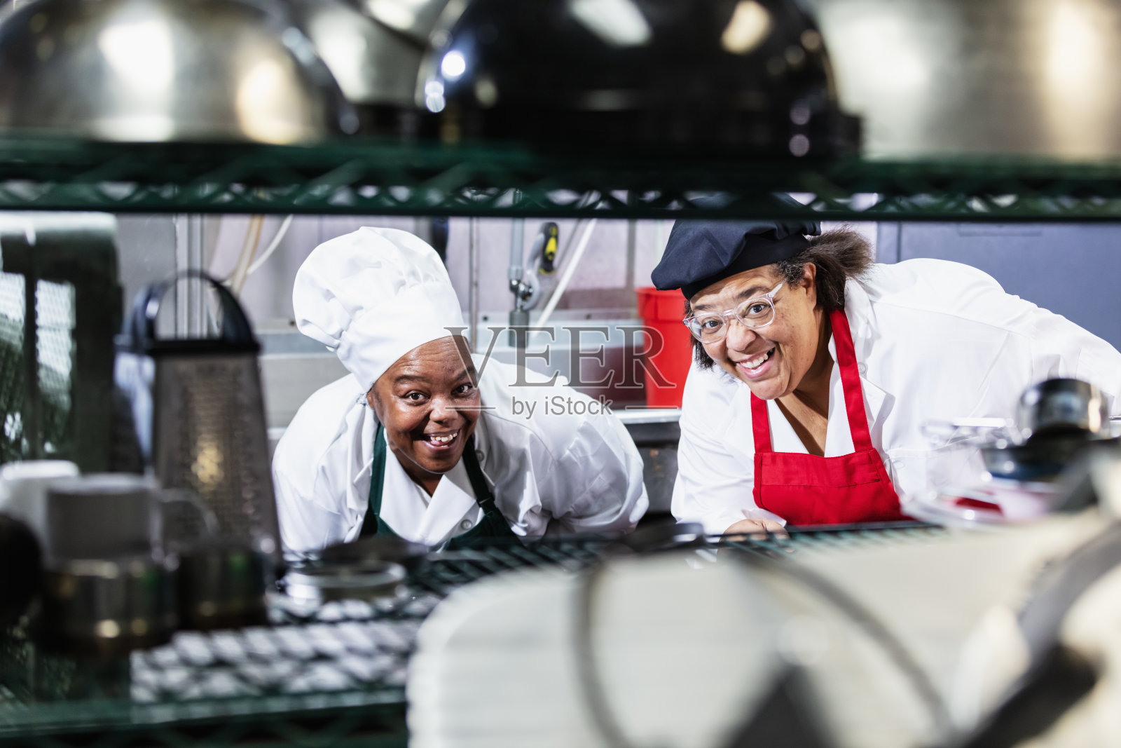 两名女性在餐厅厨房工作，面带微笑看向镜头照片摄影图片