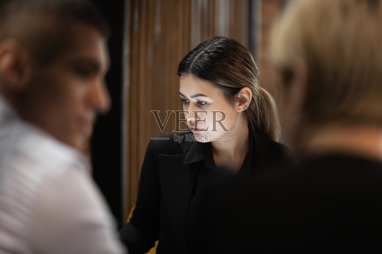 一位年轻的职业女性在现代办公室环境中与同事们深入参与商务会议。照片摄影图片