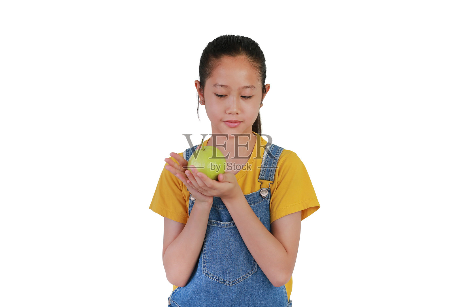 亚洲女孩手持新鲜番石榴，凝视着水果，背景为白色摄影棚。照片摄影图片