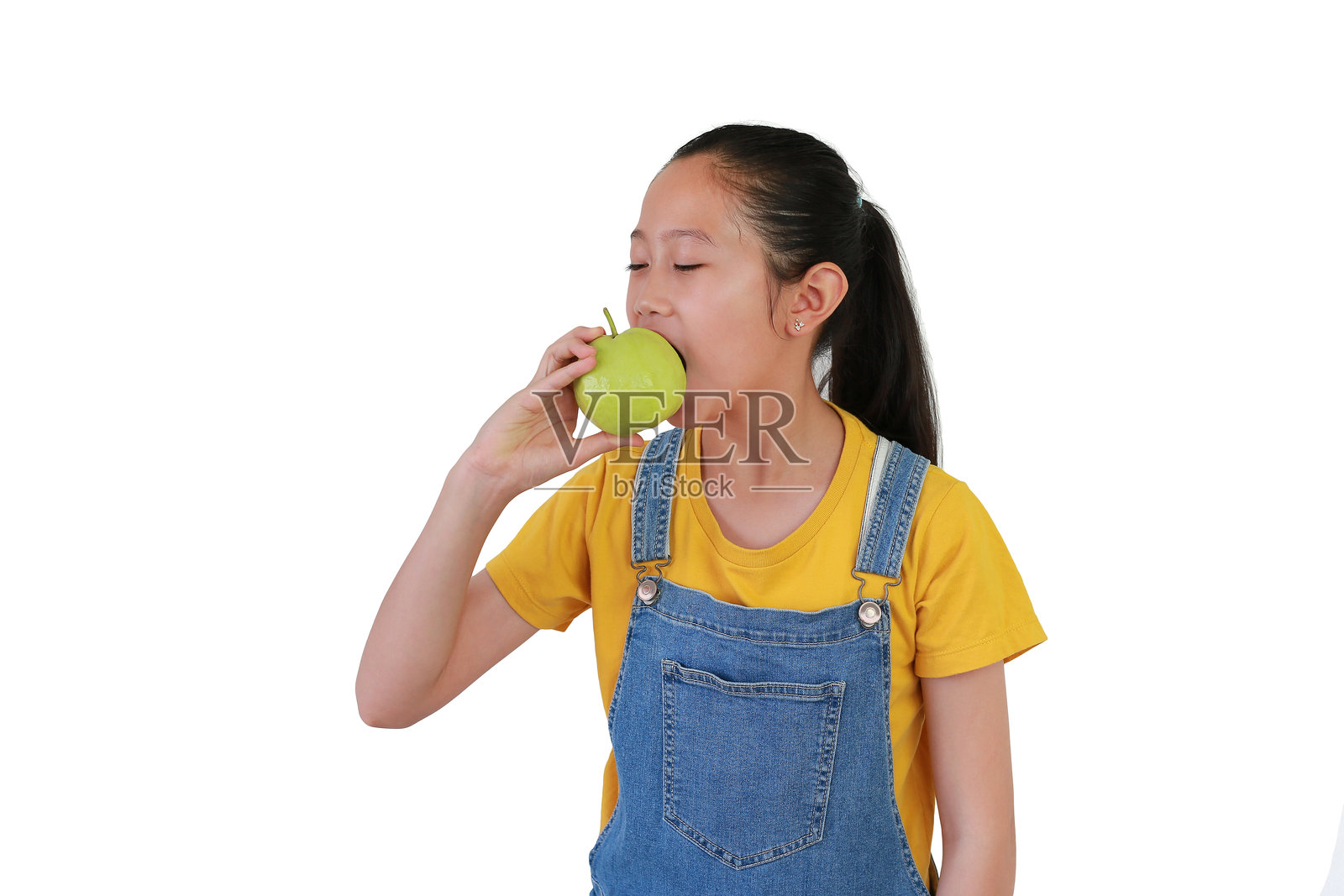 亚洲女孩在白色摄影棚背景下独自站着，吃着新鲜的番石榴。照片摄影图片