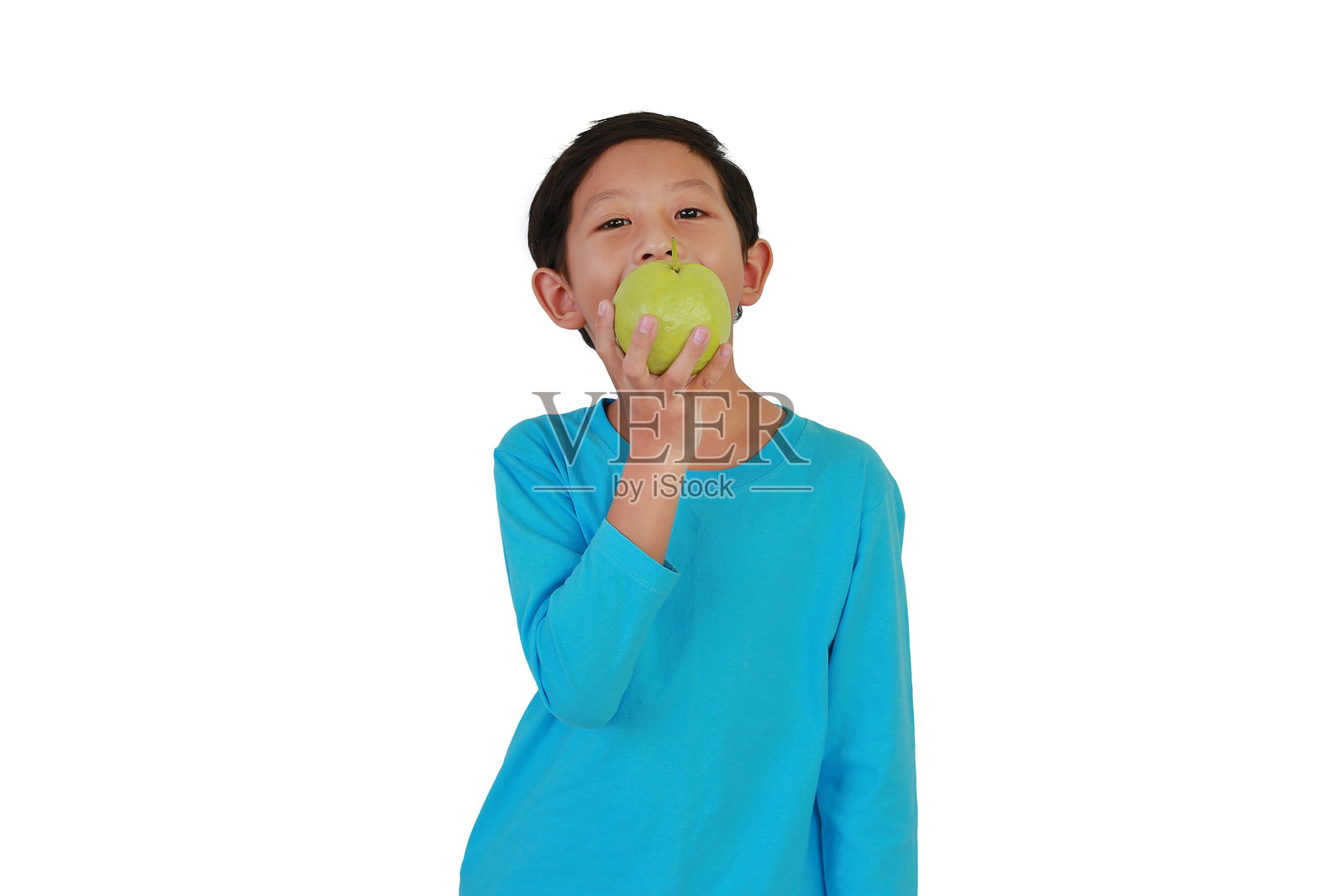 亚洲男孩在白色摄影棚背景下吃新鲜的番石榴并看向镜头。照片摄影图片