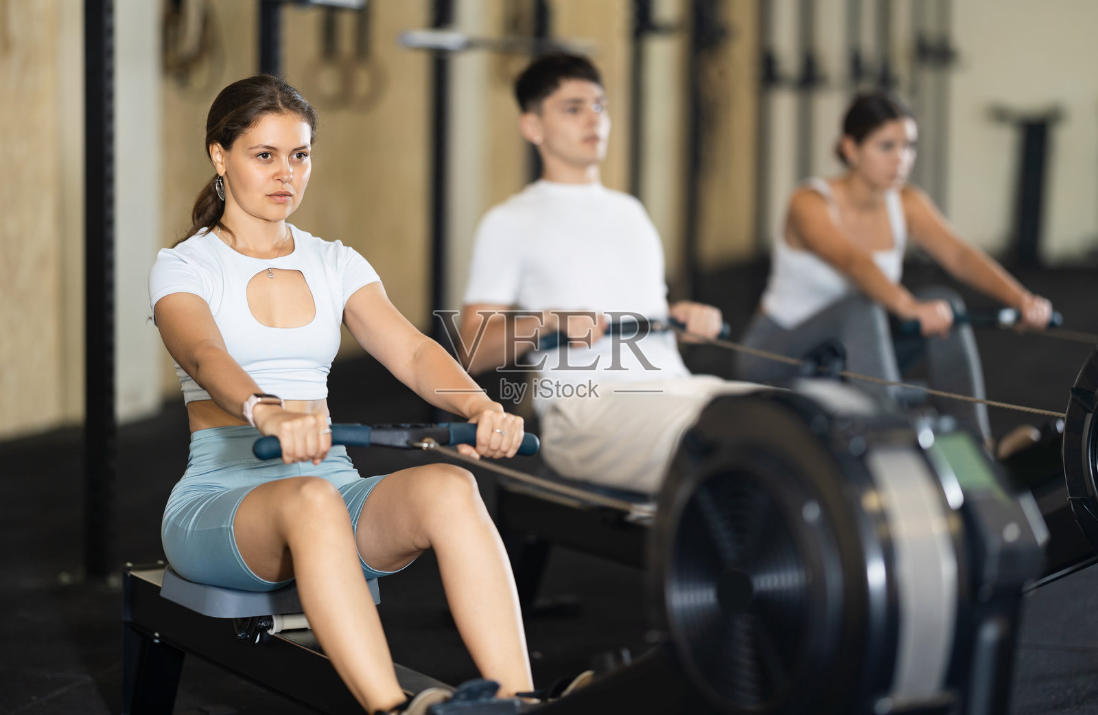 年轻女性在器械上锻炼手臂照片摄影图片