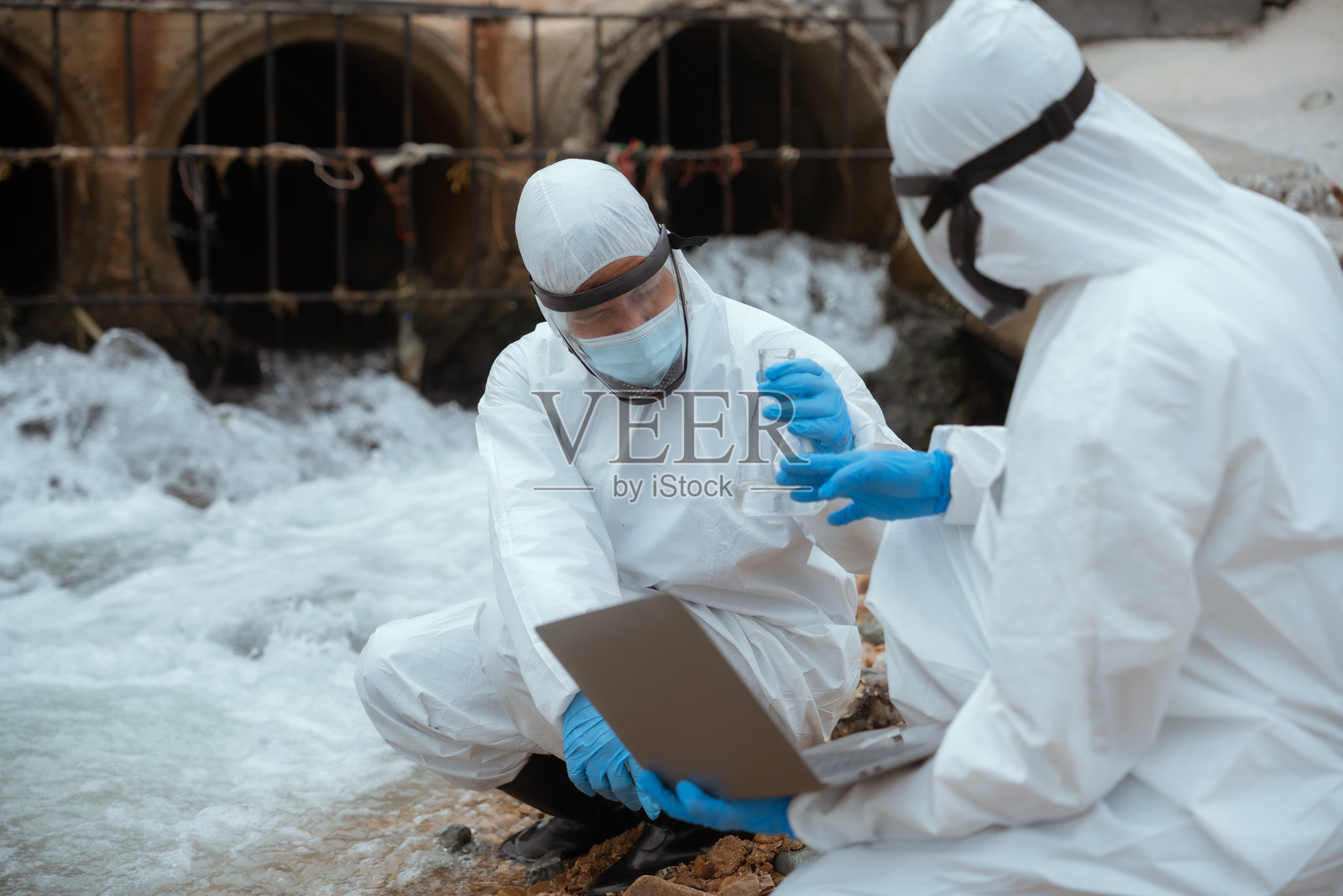 环境科学家在阴天的污染河流环境中进行水质分析照片摄影图片