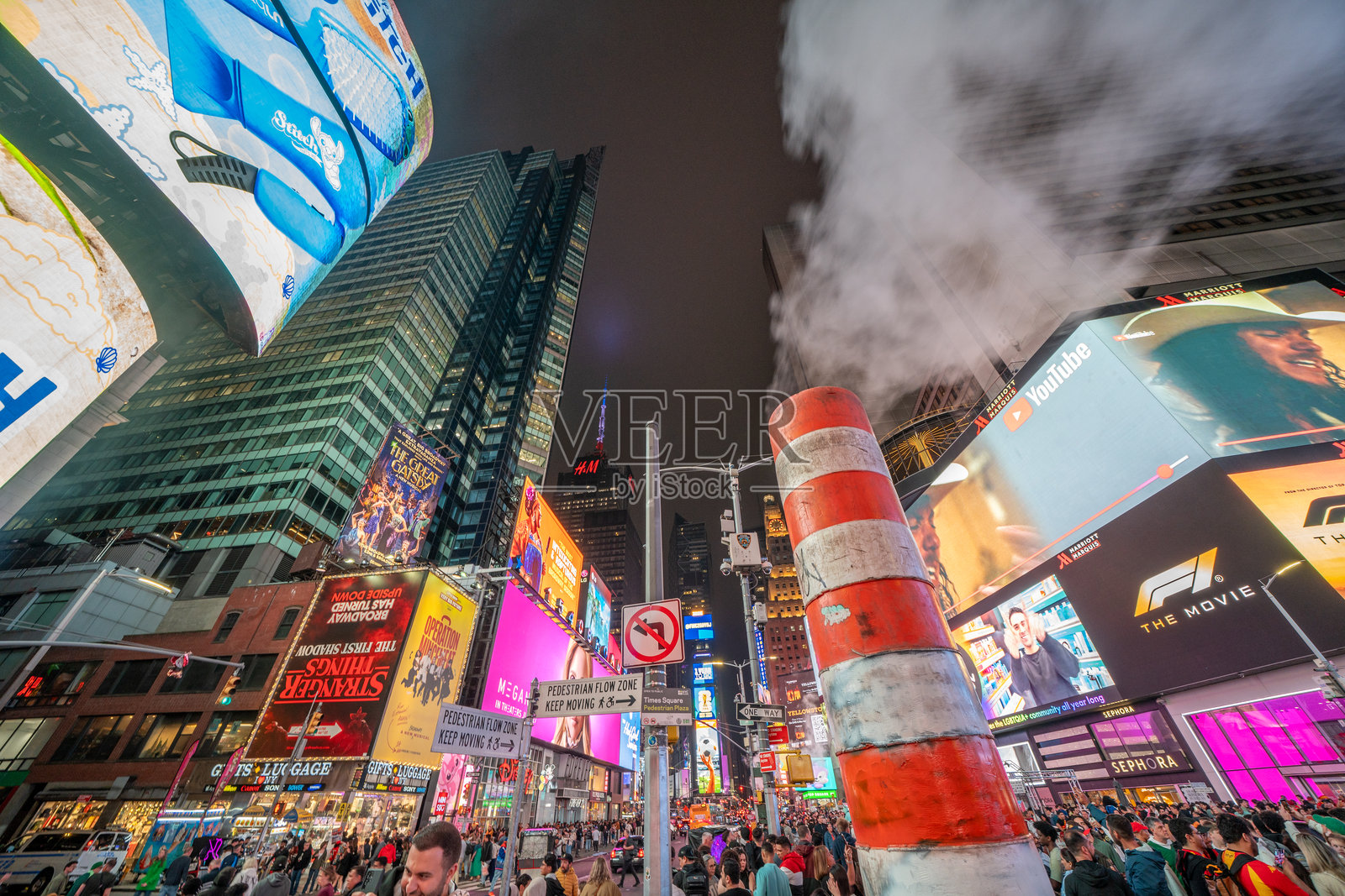 纽约市 - 2025年6月14日：夜晚的城市街景，显示出从人孔盖冒出的烟雾，周围是沥青。照片摄影图片