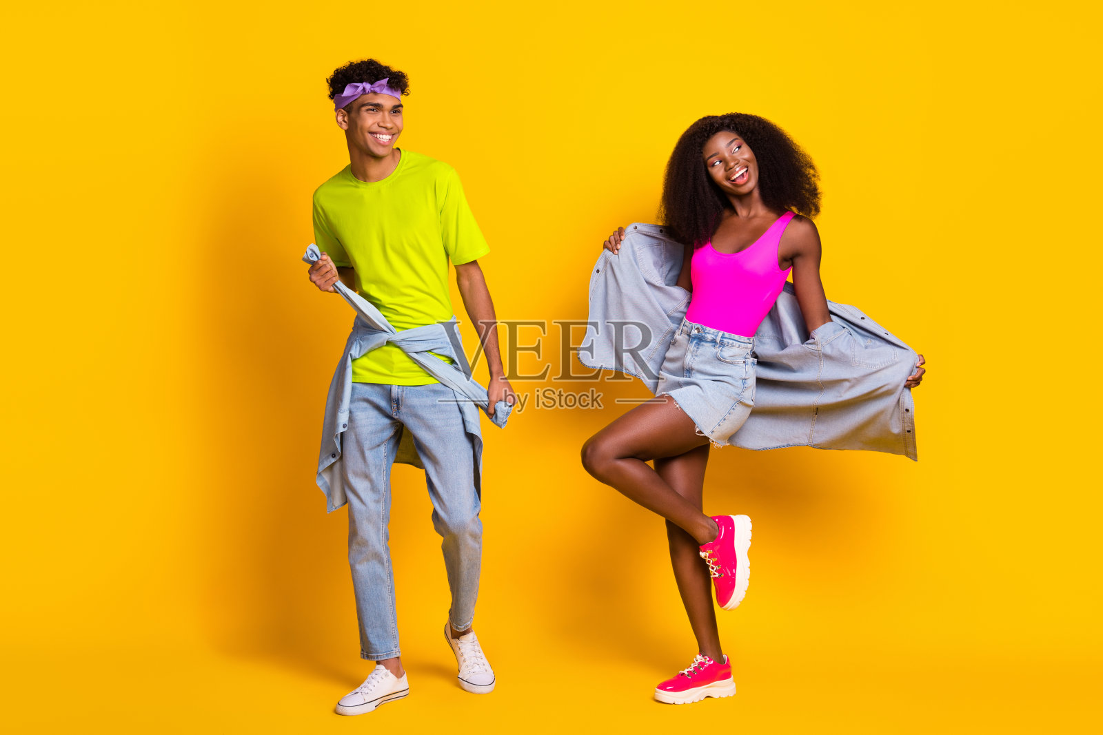 一对迷人、苗条、快乐的情侣在明亮的黄色背景下尽情舞蹈，享受欢乐时光。照片摄影图片