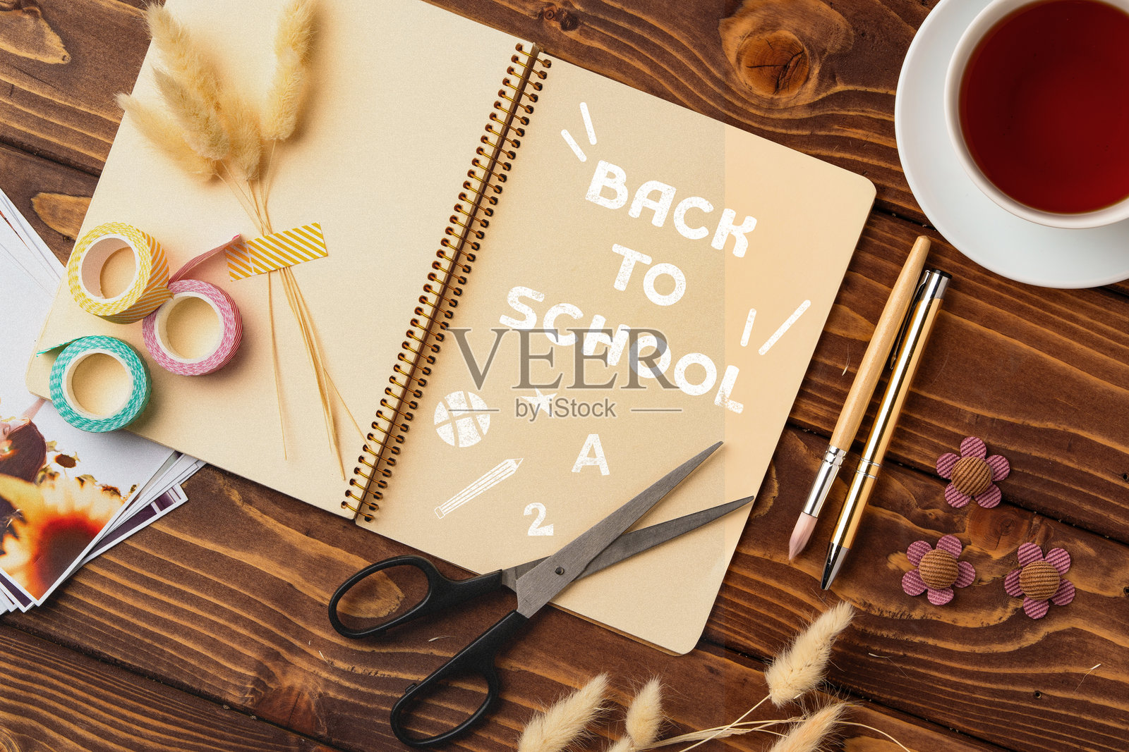 舒适的工作空间中，准备迎接返校季的文具和笔记本，旁边有一杯茶。照片摄影图片