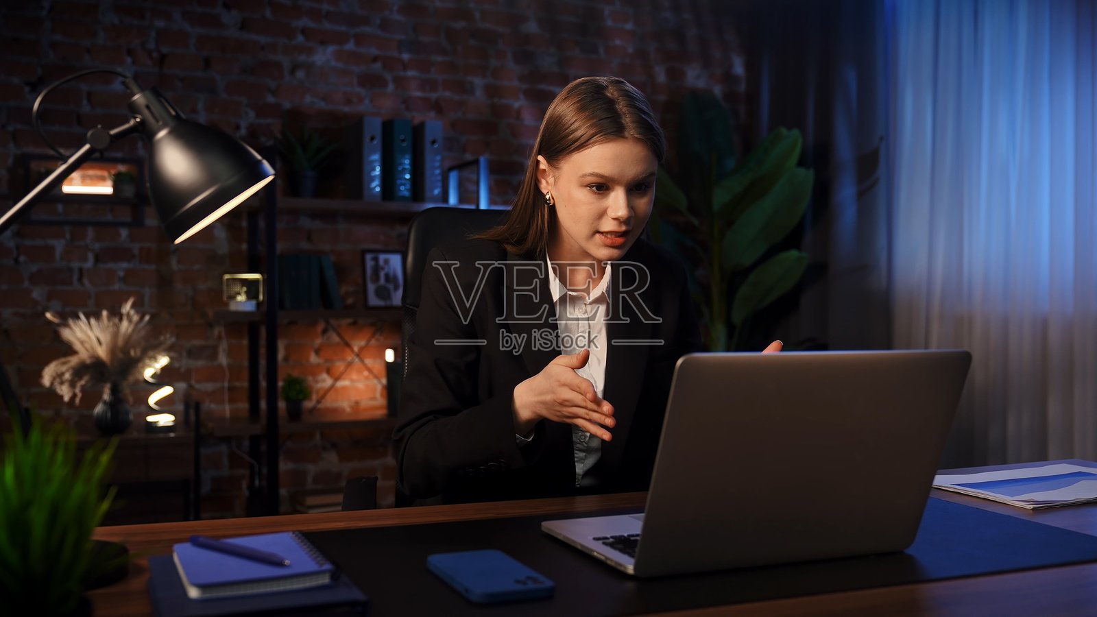 商务女性在现代办公桌前参与虚拟会议照片摄影图片