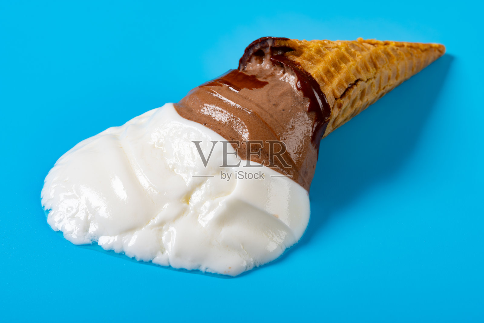 蓝色背景上的融化甜巧克力味冰淇淋蛋筒的侧面视角照片摄影图片