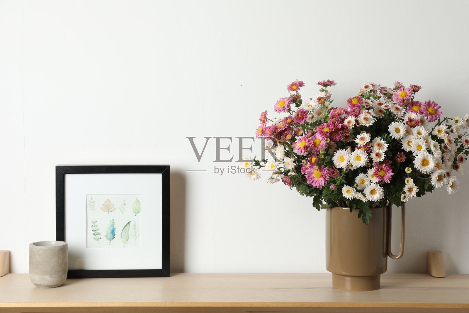 木架子上摆放着美丽花卉和其他装饰品，靠近白色墙壁。照片摄影图片