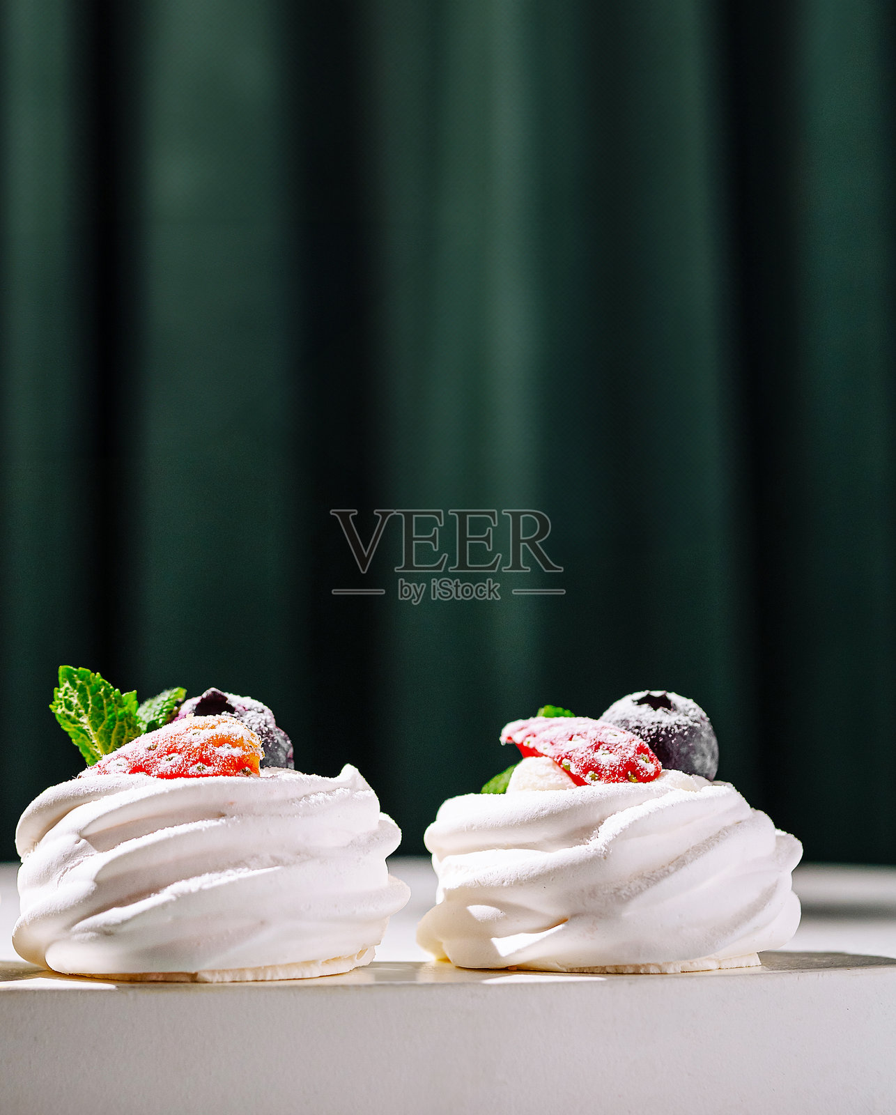 美味的蛋白霜甜点，上面装饰着新鲜水果，摆放在桌子上照片摄影图片