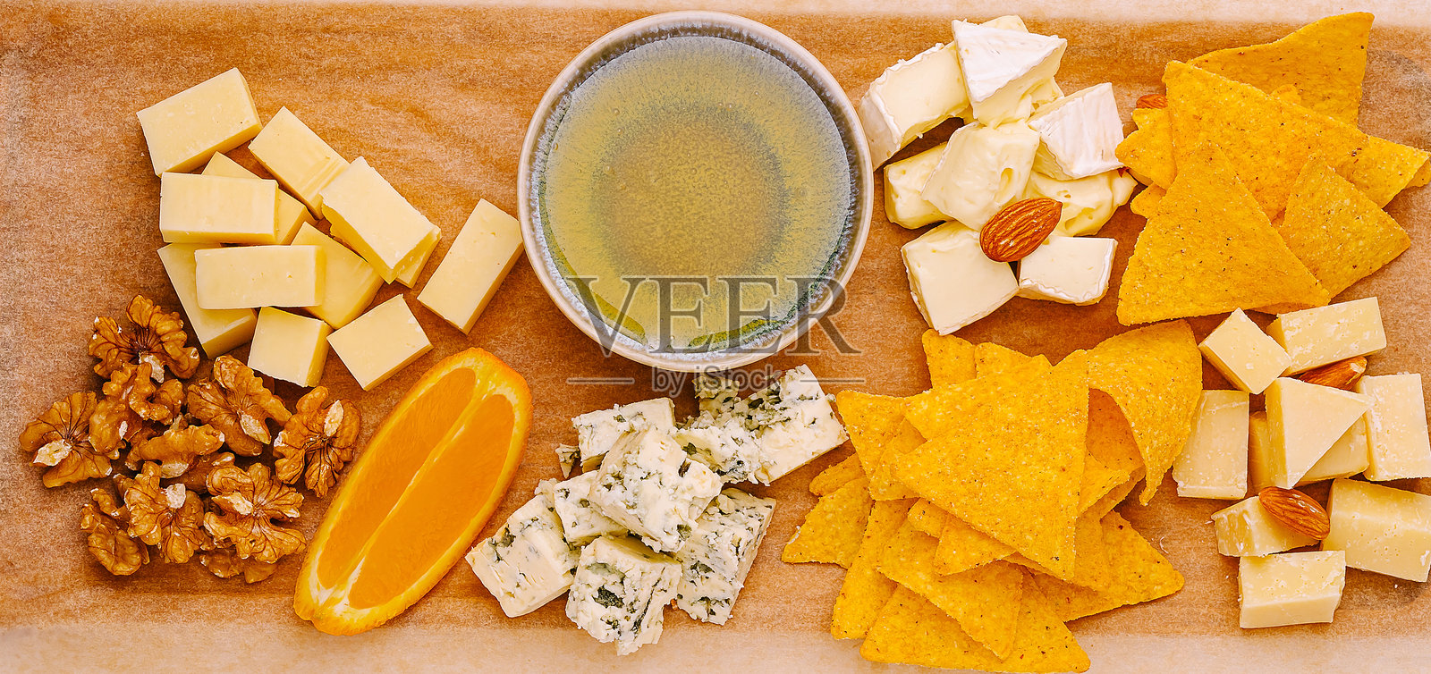 奶酪和小吃拼盘展示在木板上，配有坚果和柑橘。照片摄影图片