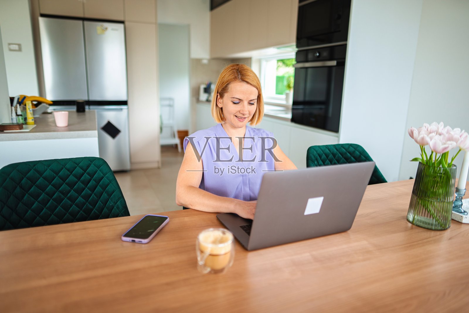 在家工作的女性坐在餐桌旁使用笔记本电脑照片摄影图片