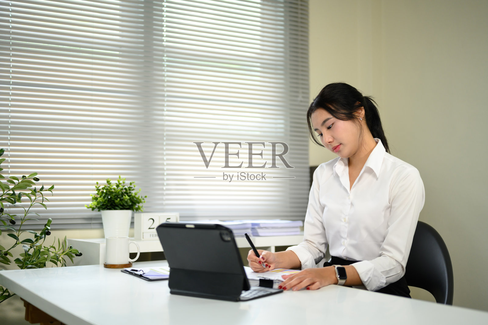 自信的年轻女商人在办公室使用平板电脑制定战略。照片摄影图片