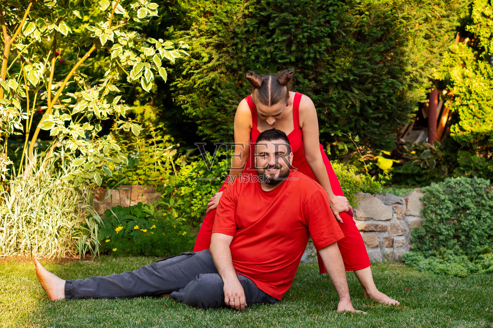 在阳光明媚的花园里，情侣们调皮地摆姿势，举起双手。照片摄影图片