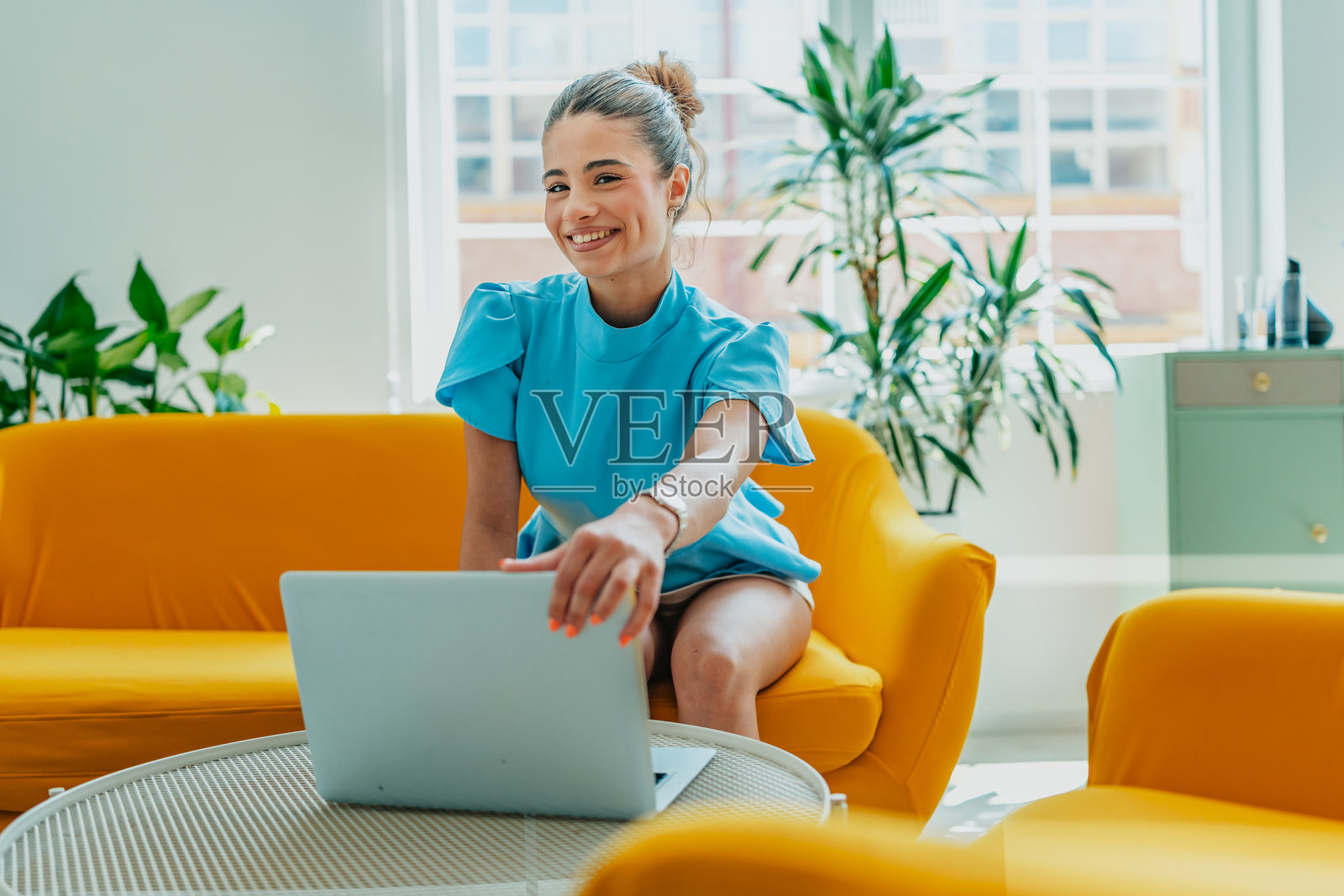 年轻女性在明亮舒适的客厅里使用笔记本电脑，享受在家工作的时光照片摄影图片