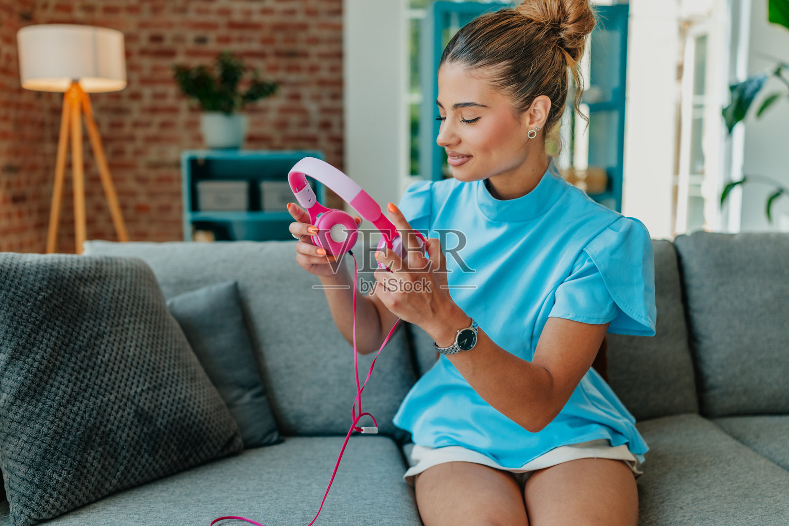 年轻女性在明亮的客厅里戴着耳机享受音乐，放松身心。照片摄影图片