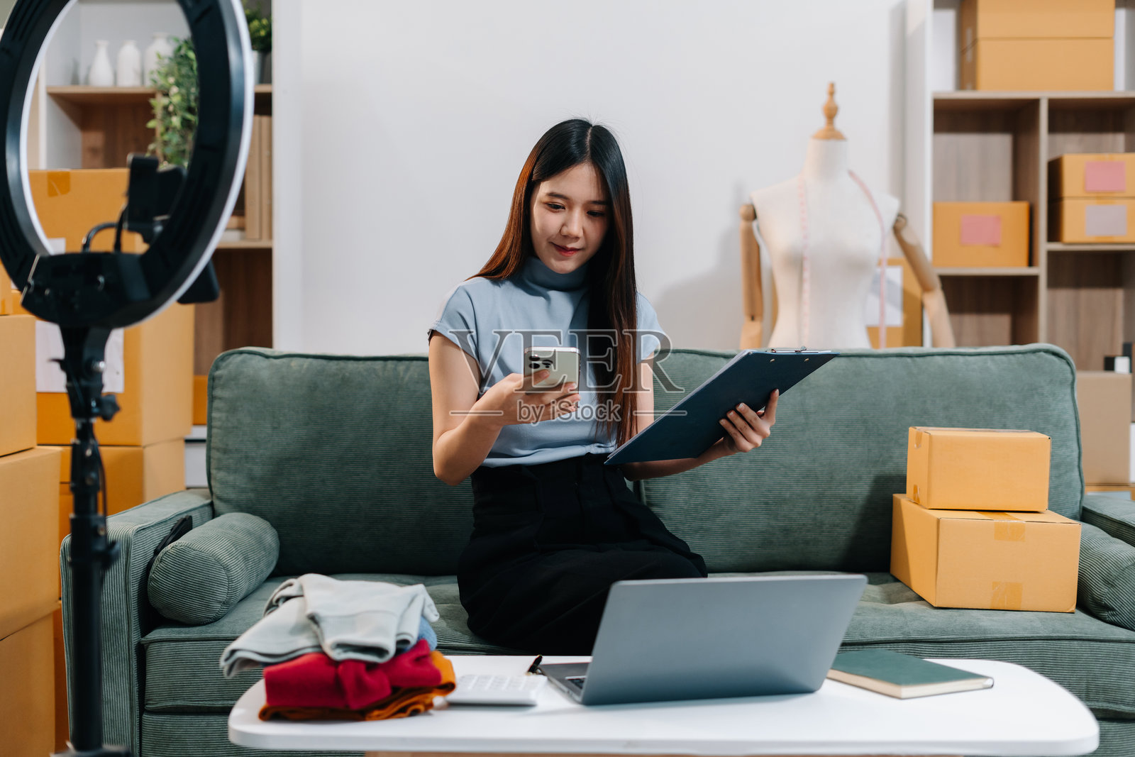 店主微笑着享受在线直播销售，使用智能手机在家工作。照片摄影图片