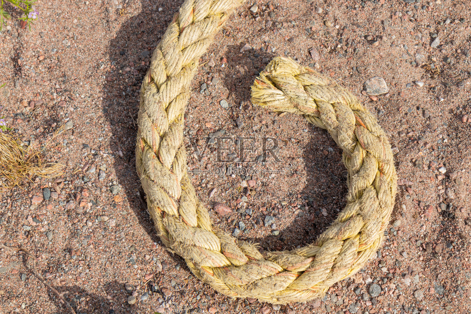 沙滩上躺着一根绳子的末端，唤起海洋生活和海边的简单。一个极简的海洋细节，代表着连接、休闲和宁静的海岸时光。照片摄影图片