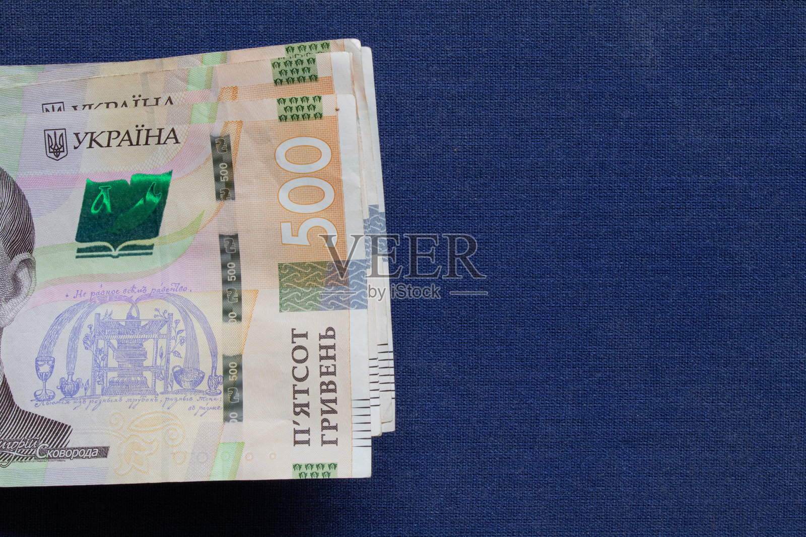 一包50和500乌克兰格里夫纳纸币放在蓝色布面上，商务场景照片摄影图片