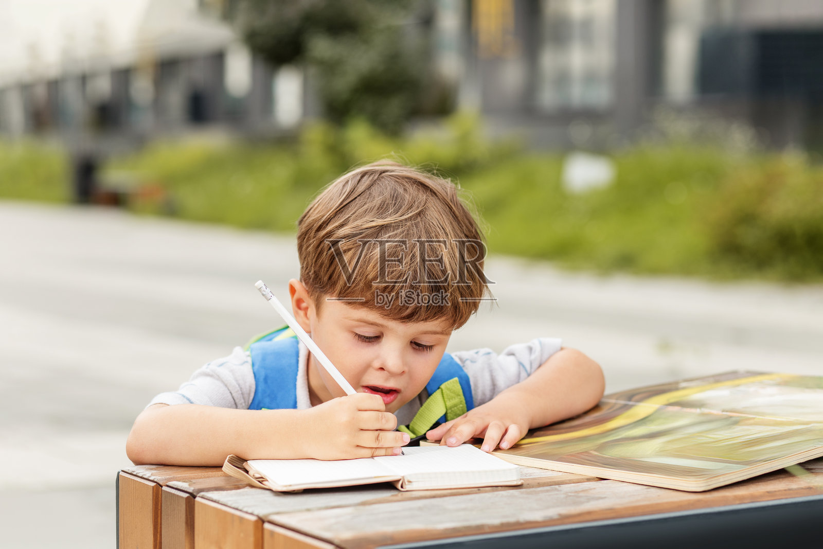 专注的小男孩在户外写笔记本照片摄影图片