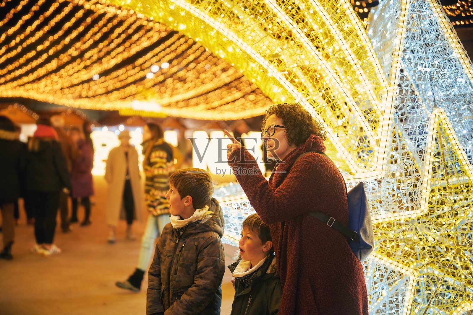 母亲和孩子们在节日夜市享受圣诞灯光装置照片摄影图片