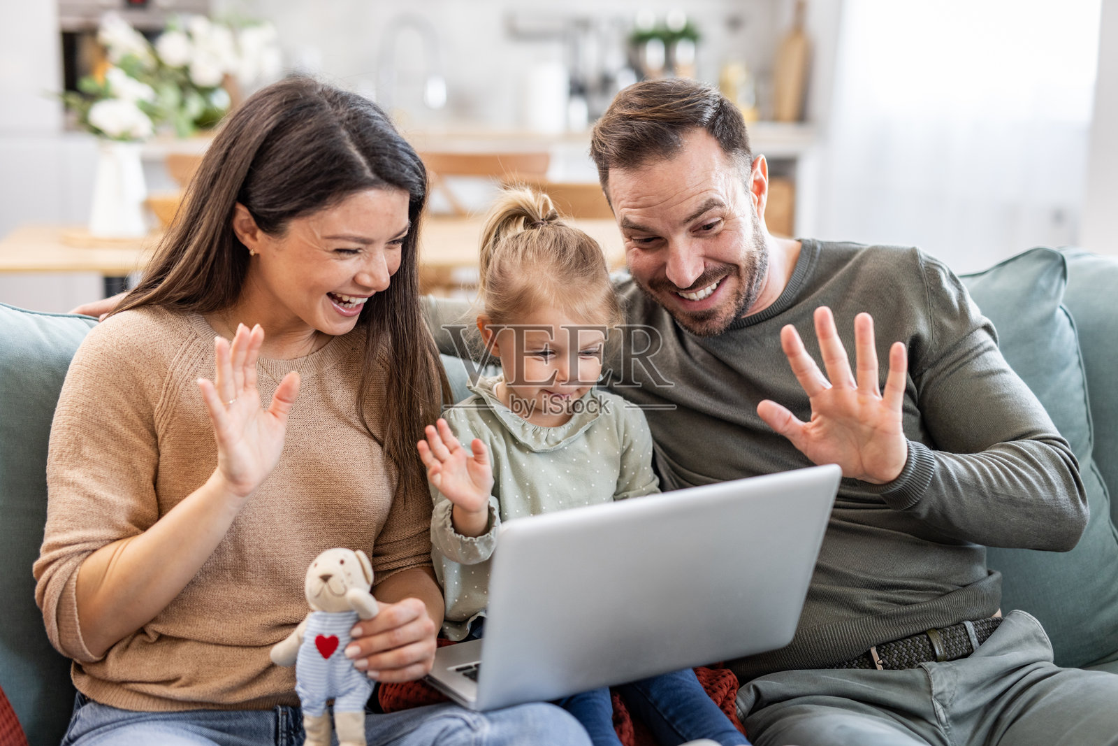 快乐的家庭在家中通过视频通话向笔记本电脑挥手致意照片摄影图片