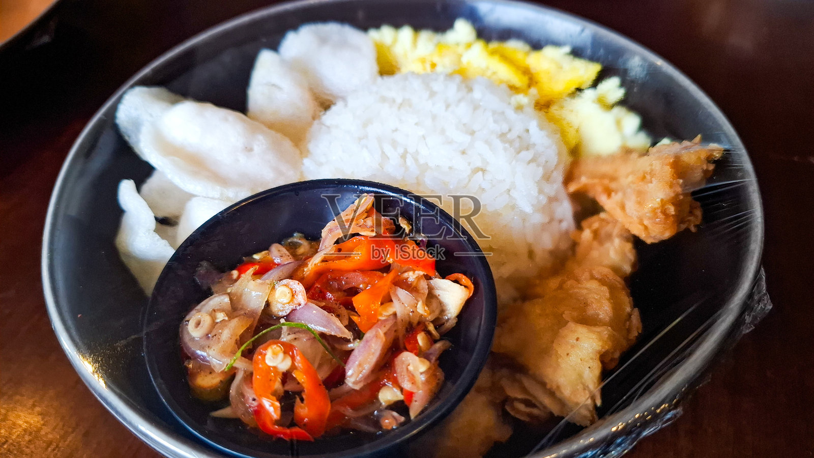 印尼米饭拼盘，配炸鸡、炒蛋、虾片和辣椒调味料照片摄影图片