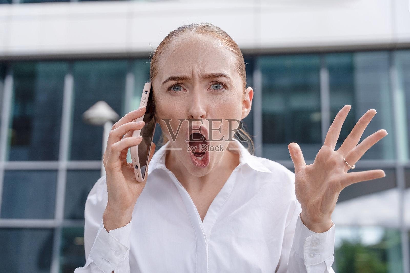 女性在办公大楼外白天打电话时表达沮丧情绪照片摄影图片