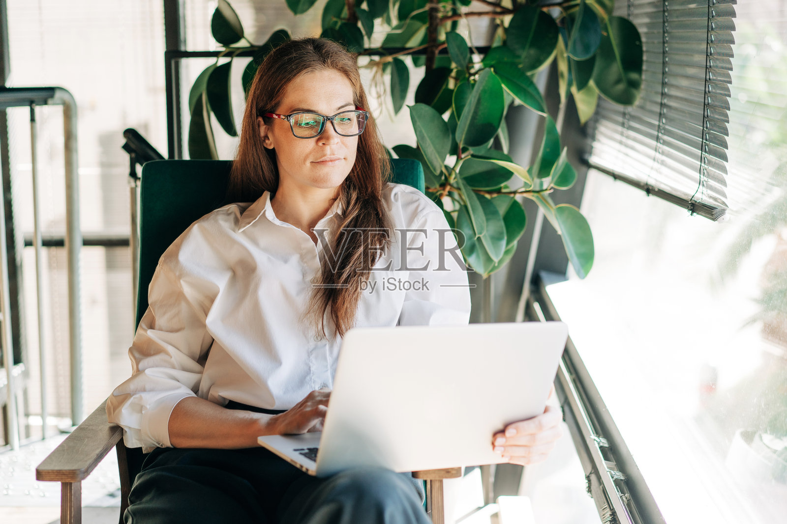 一位美丽的有雀斑的红发白人女性坐在一个舒适的房间里，正在使用笔记本电脑。照片摄影图片