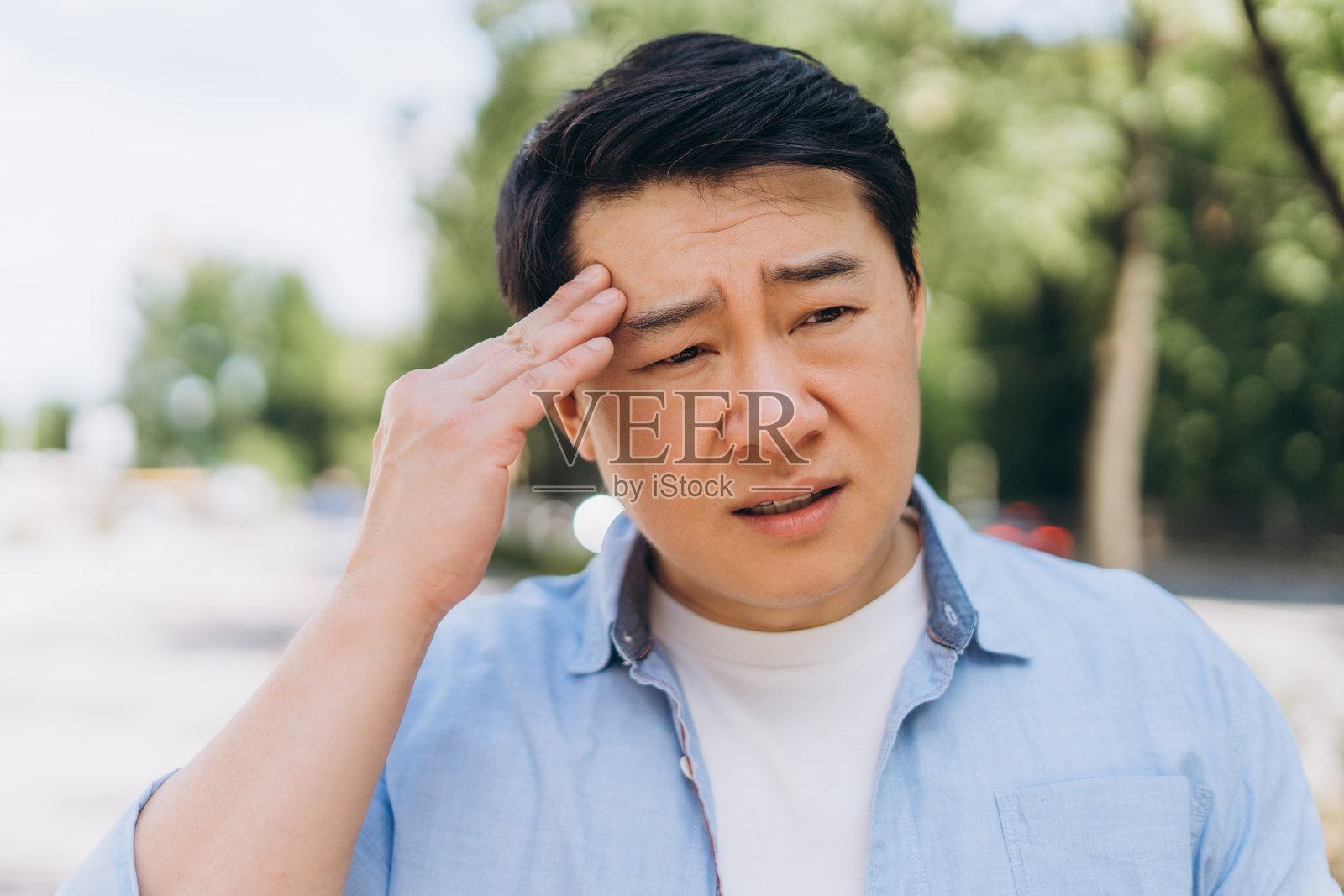 户外一名亚洲男子因头痛而捂住额头照片摄影图片