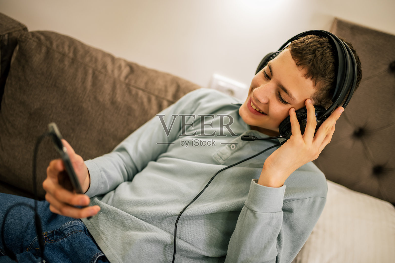 小男孩在公寓里公路旅行，戴着耳机用手机。照片摄影图片