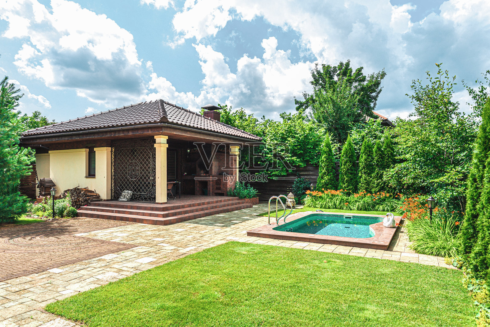 美丽的花园，配有舒适的房子和游泳池，白天宁静的户外环境。照片摄影图片